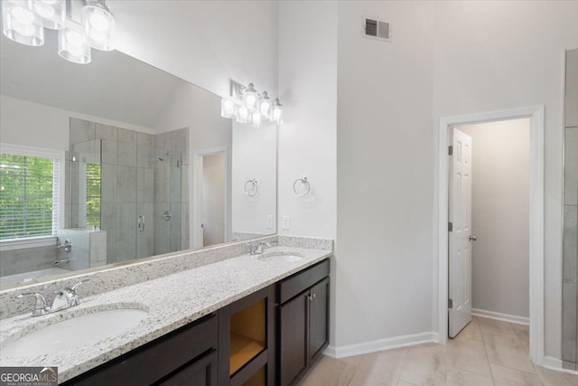 bathroom featuring a stall shower, lofted ceiling, double vanity, a bath, and baseboards