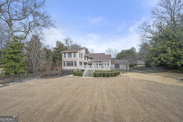 back of property with a fenced backyard, a wooden deck, stairway, and a shingled roof