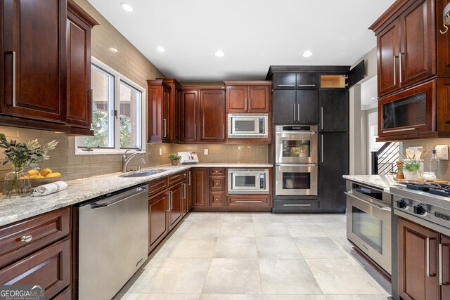 kitchen featuring recessed lighting, a sink, backsplash, and appliances with stainless steel finishes