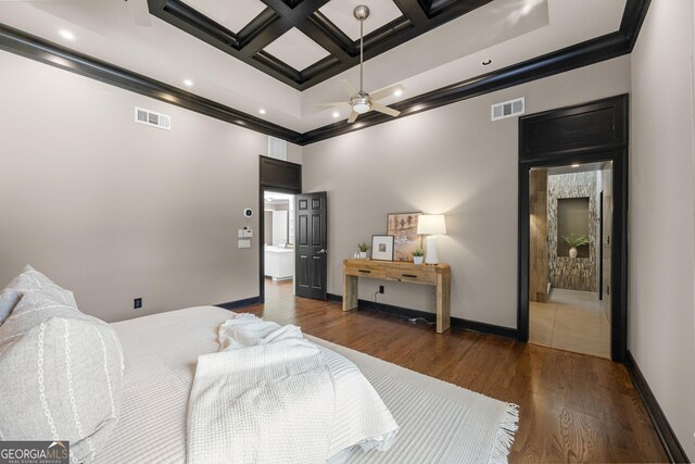 bedroom featuring coffered ceiling, crown molding, wood finished floors, and visible vents