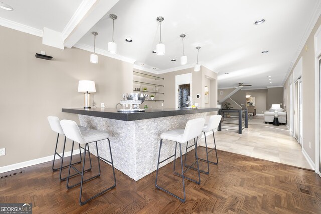 kitchen with ceiling fan, baseboards, a breakfast bar area, and ornamental molding