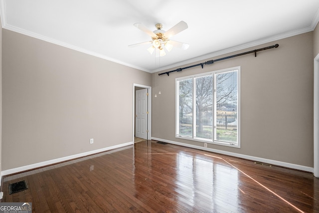 spare room with wood finished floors, visible vents, a ceiling fan, crown molding, and baseboards