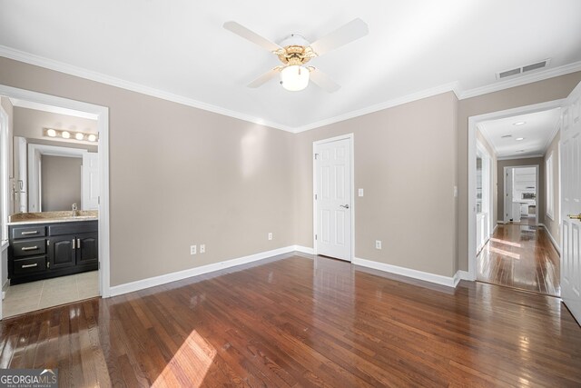 unfurnished bedroom with wood finished floors, visible vents, and crown molding