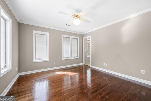 spare room featuring baseboards, ornamental molding, wood finished floors, and visible vents