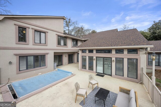 rear view of property featuring stucco siding, a patio area, and a shingled roof