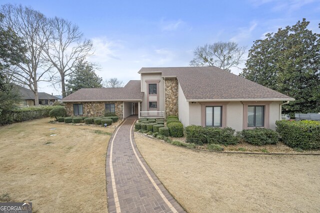 mid-century home with roof with shingles, stone siding, and stucco siding