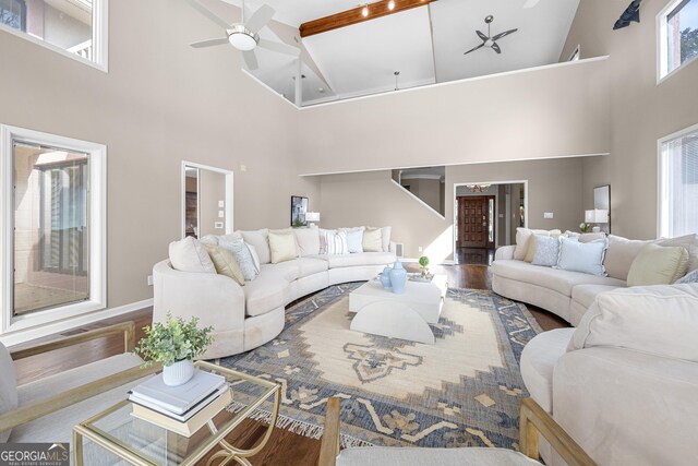 living room featuring high vaulted ceiling, a ceiling fan, wood finished floors, and beamed ceiling