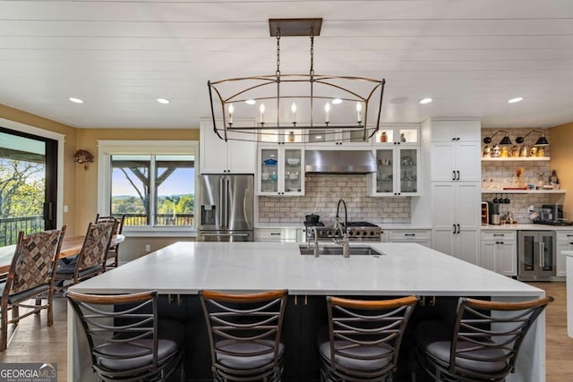 kitchen featuring stainless steel refrigerator with ice dispenser, light wood-style flooring, a sink, and beverage cooler
