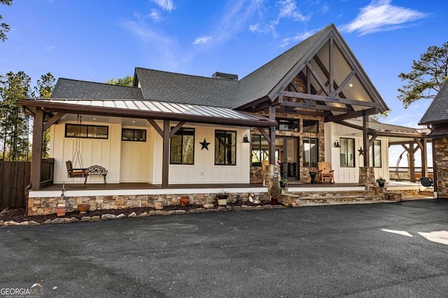 view of front facade featuring a porch, a standing seam roof, metal roof, and fence