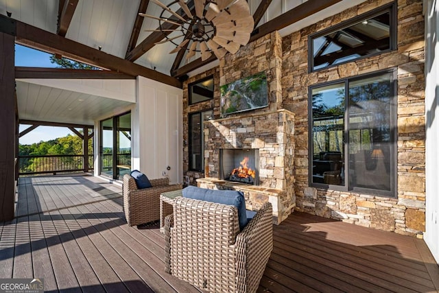 wooden deck featuring an outdoor stone fireplace and a ceiling fan