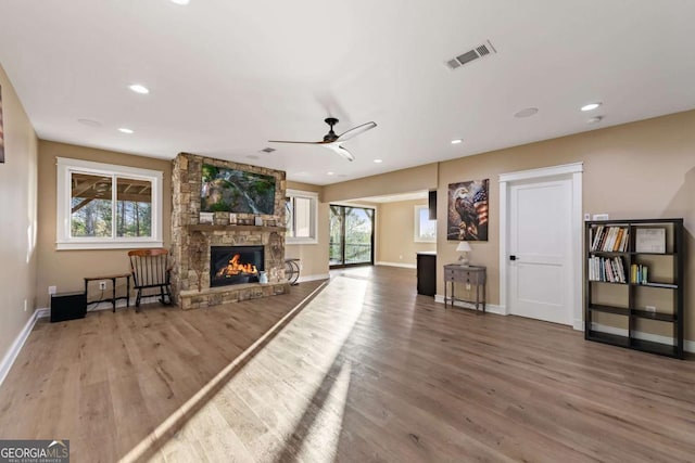 unfurnished living room with a fireplace, wood finished floors, visible vents, and baseboards