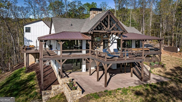 rear view of property with a deck, metal roof, roof with shingles, and a patio