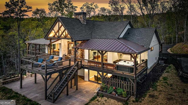 back of house with a standing seam roof, metal roof, a wooden deck, a patio area, and a shingled roof