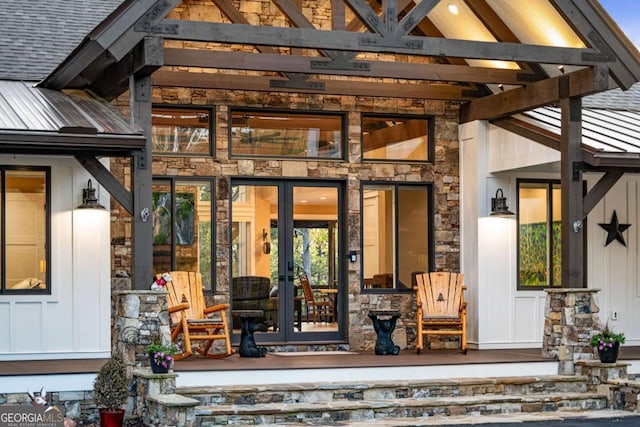view of exterior entry featuring board and batten siding, french doors, and stone siding
