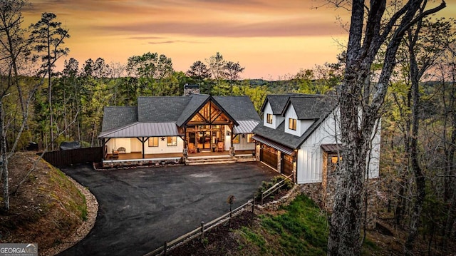 view of front of property with a chimney, driveway, an attached garage, metal roof, and a standing seam roof