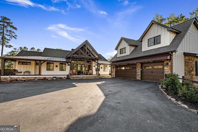 modern inspired farmhouse featuring aphalt driveway, stone siding, board and batten siding, a porch, and roof with shingles