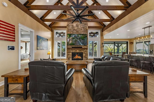 living room featuring a stone fireplace, wood finished floors, and beamed ceiling