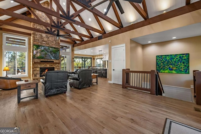 living area with beamed ceiling, wood finished floors, a fireplace, and high vaulted ceiling