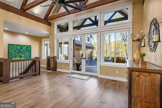 entryway with baseboards, beamed ceiling, a ceiling fan, wood finished floors, and high vaulted ceiling