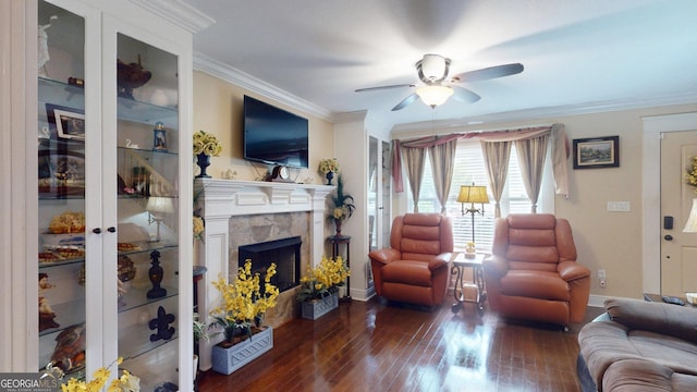 living room featuring a high end fireplace, a ceiling fan, wood-type flooring, crown molding, and baseboards