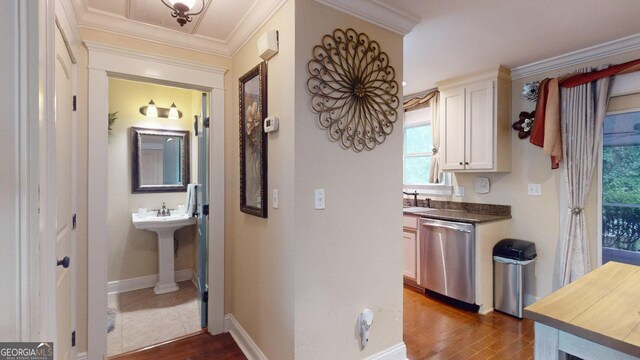interior space with dark wood-type flooring, baseboards, ornamental molding, and a sink