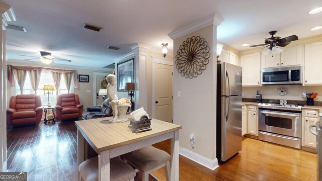 kitchen featuring open floor plan, a ceiling fan, stainless steel appliances, and light wood-style flooring