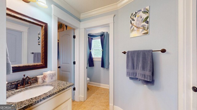 bathroom with vanity, baseboards, toilet, ornamental molding, and tile patterned flooring