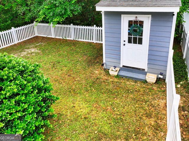 view of yard with an outdoor structure, a fenced backyard, and a storage shed