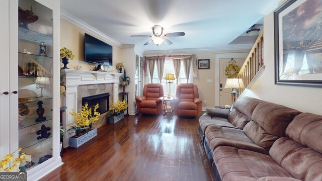 living room with a ceiling fan, wood-type flooring, crown molding, a fireplace, and stairs