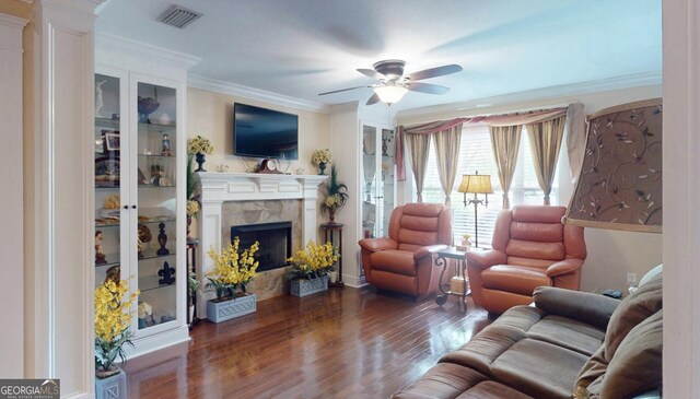 living room featuring visible vents, a ceiling fan, wood finished floors, a fireplace, and ornamental molding