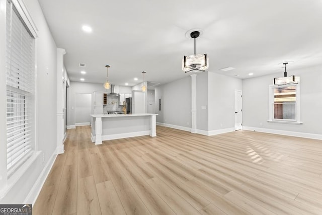 unfurnished living room with light wood finished floors, baseboards, and recessed lighting