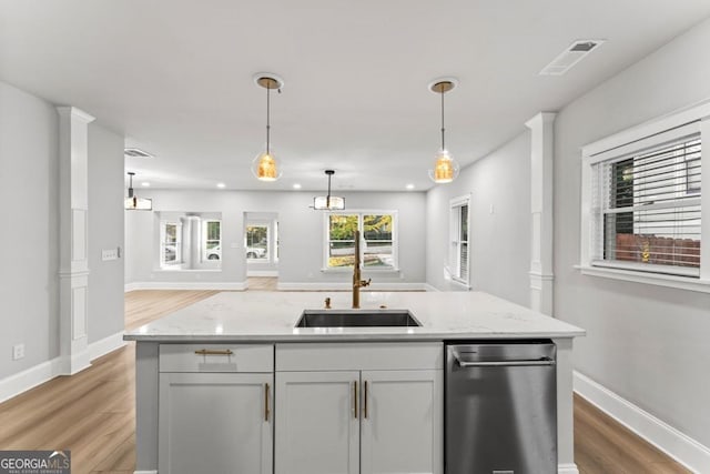 kitchen featuring stainless steel dishwasher, light wood-style flooring, a sink, open floor plan, and visible vents