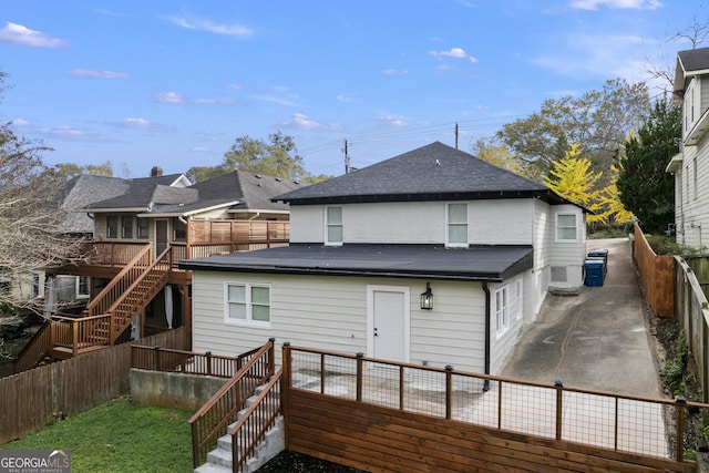 back of house featuring a wooden deck, a fenced backyard, roof with shingles, and stairs
