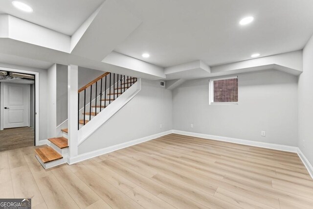 finished below grade area with light wood-style flooring, baseboards, recessed lighting, and stairs