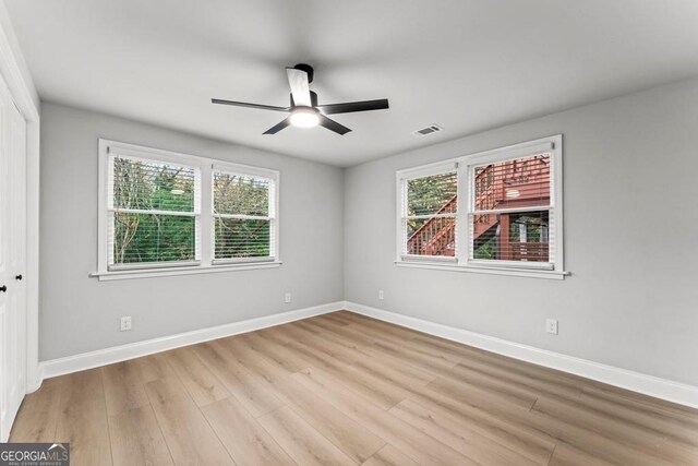 unfurnished room featuring light wood-style floors, visible vents, a ceiling fan, and a healthy amount of sunlight