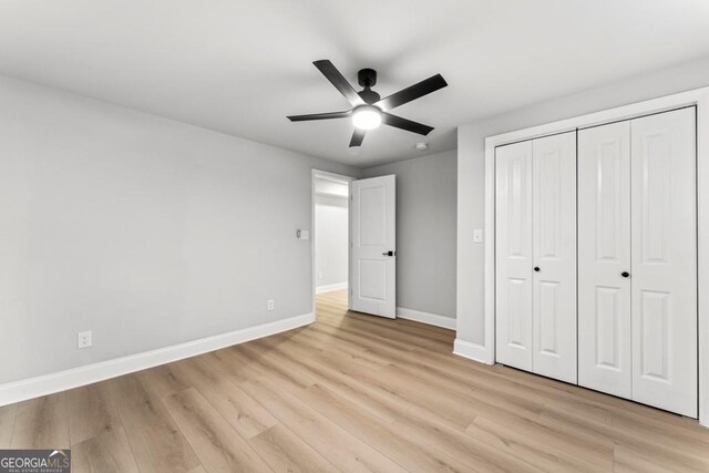 unfurnished bedroom with ceiling fan, baseboards, a closet, and light wood-style flooring