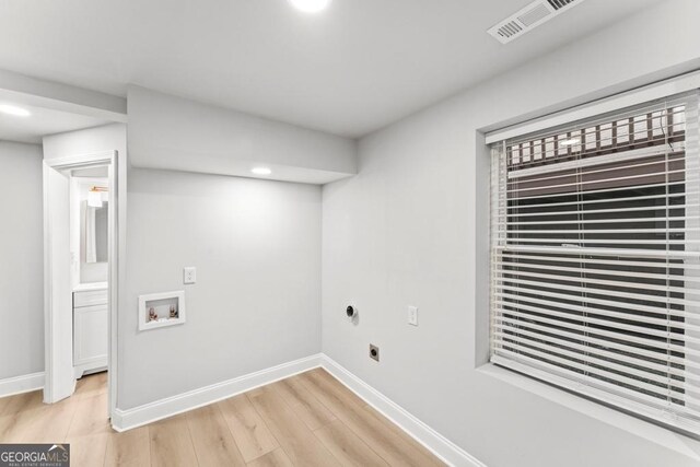 clothes washing area with light wood finished floors, hookup for an electric dryer, baseboards, washer hookup, and laundry area