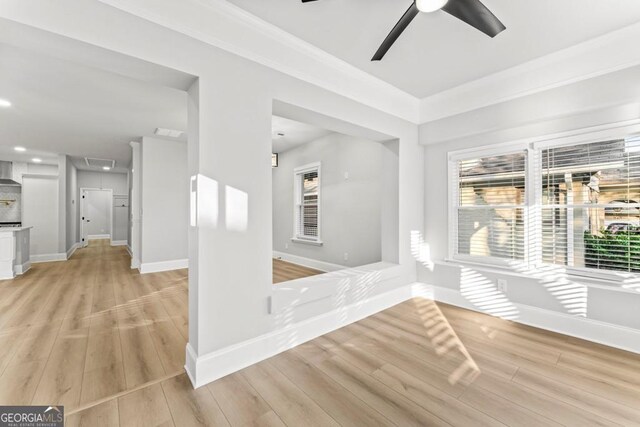 spare room featuring attic access, baseboards, a ceiling fan, and light wood-style floors