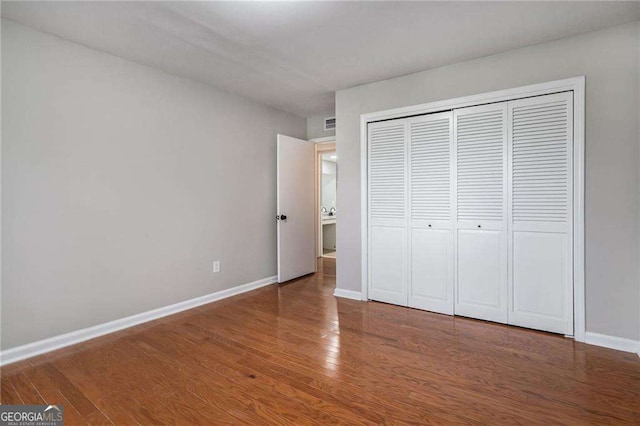 unfurnished bedroom featuring wood finished floors, a closet, and baseboards