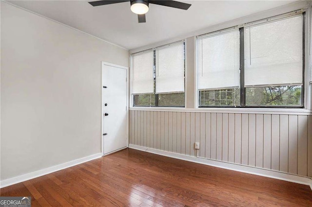 unfurnished room featuring wood-type flooring, a healthy amount of sunlight, a ceiling fan, and baseboards