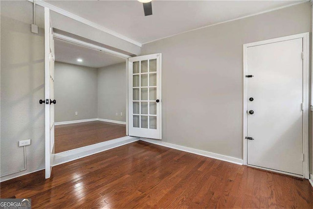 empty room with baseboards, crown molding, french doors, and wood finished floors