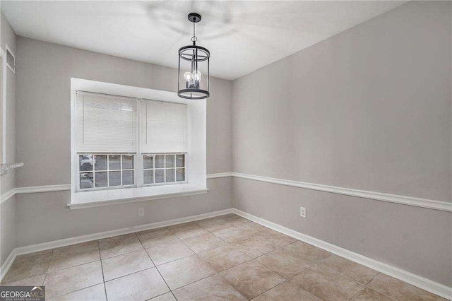 unfurnished dining area with tile patterned floors, baseboards, and a notable chandelier
