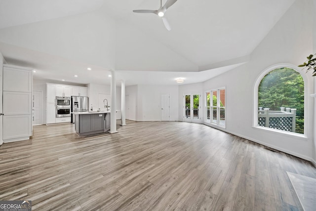 515 Old Chartwell Xing, Alpharetta, GA 30022 - unfurnished living room with a ceiling fan, a sink, high vaulted ceiling, baseboards, and light wood-style floors