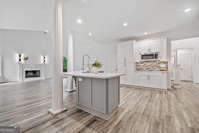 515 Old Chartwell Xing, Alpharetta, GA 30022 - kitchen with light wood-style floors, stainless steel microwave, ornate columns, and white cabinetry