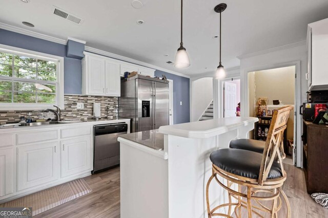 3999 Wabash Ln, Ellenwood, GA 30294 - kitchen with crown molding, light wood-style flooring, appliances with stainless steel finishes, visible vents, and a kitchen island