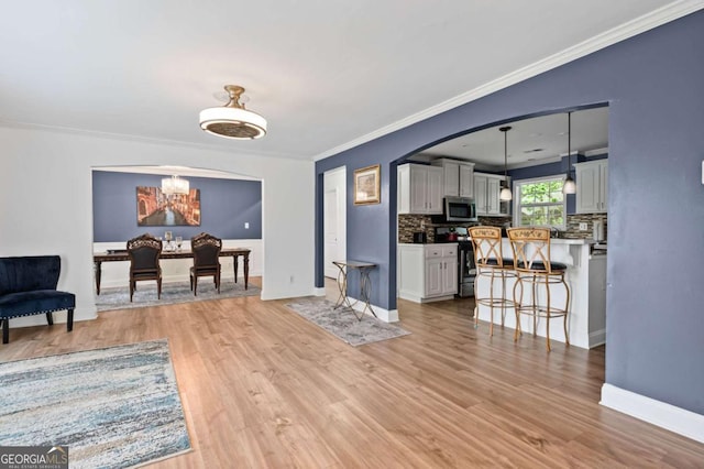 3999 Wabash Ln, Ellenwood, GA 30294 - living area with ornamental molding, light wood finished floors, baseboards, and a notable chandelier