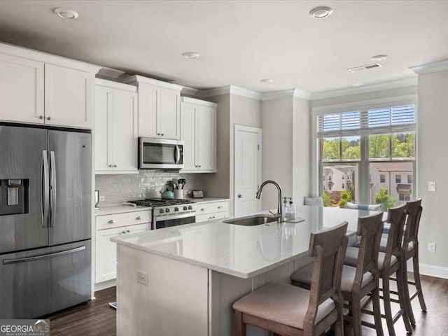 kitchen featuring stainless steel appliances, a sink, a center island with sink, dark wood finished floors, and crown molding
