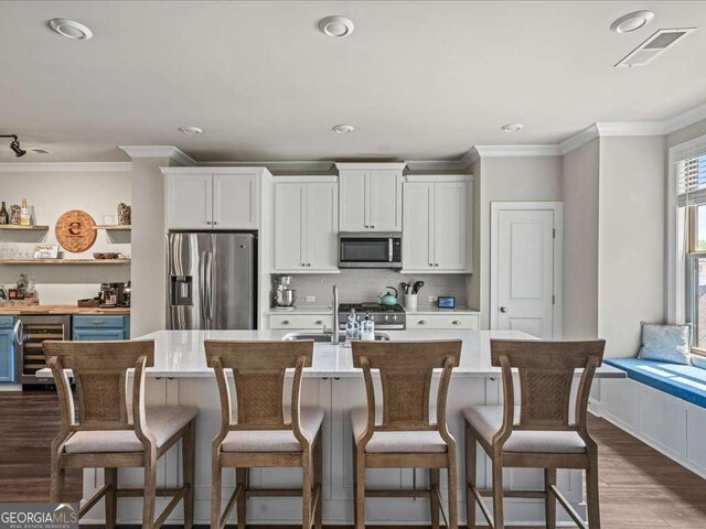 kitchen featuring wine cooler, a sink, visible vents, crown molding, and appliances with stainless steel finishes