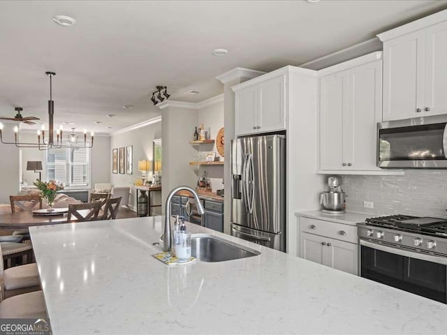 kitchen with crown molding, a sink, stainless steel appliances, a kitchen bar, and white cabinetry