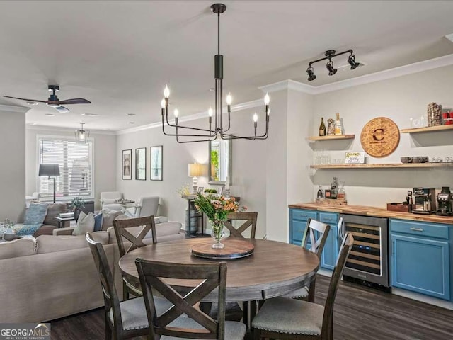 dining space with a dry bar, ceiling fan with notable chandelier, beverage cooler, dark wood-type flooring, and ornamental molding
